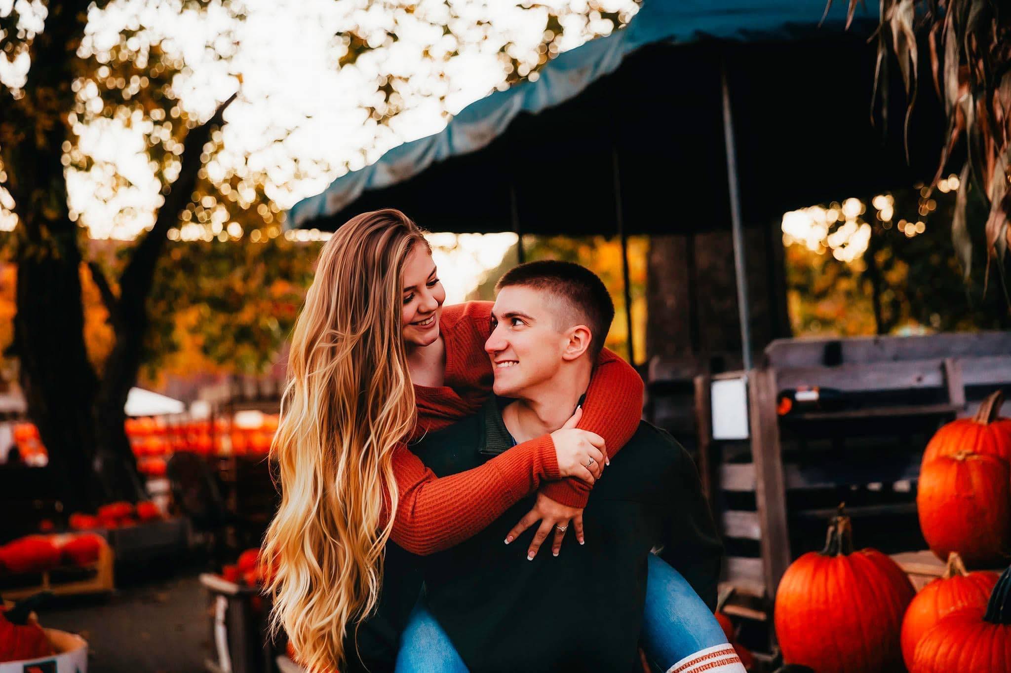 husband carries wife thorugh pumpkin farm in playful fun wway