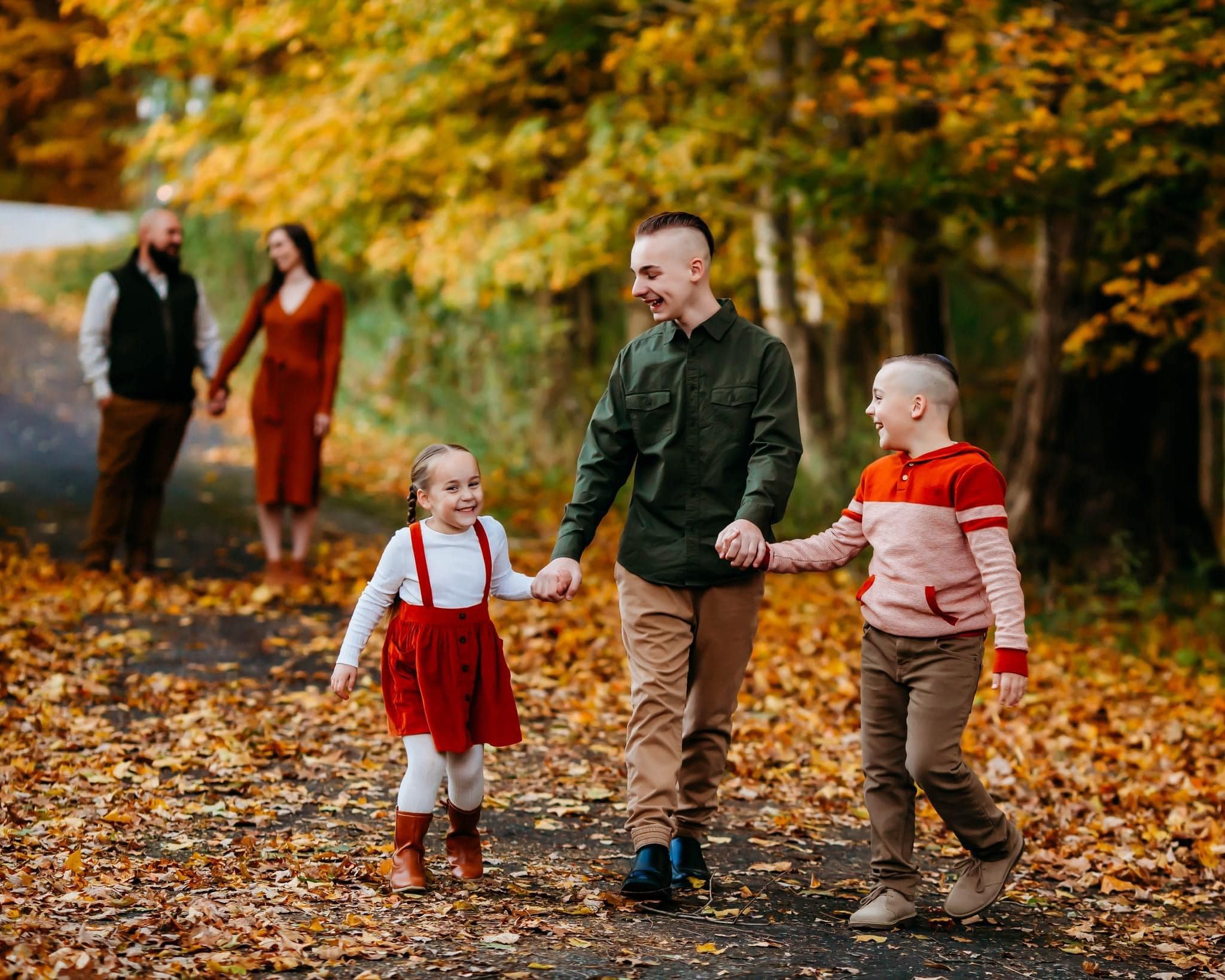 kids walking togehter laughing with their parents behind them.