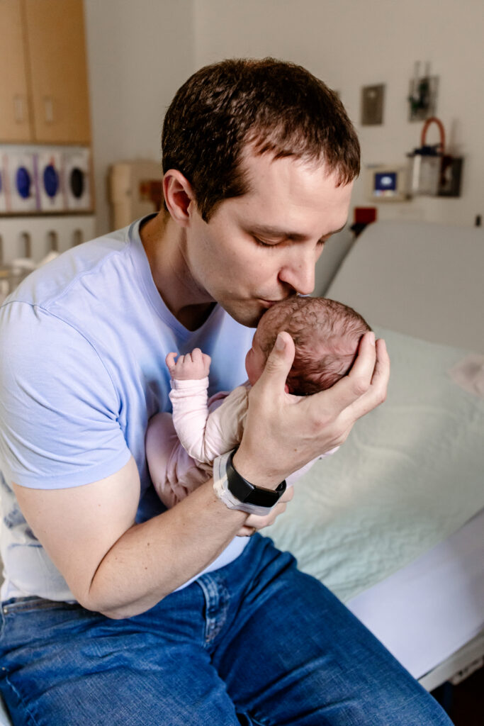 Dad kissing newborn baby