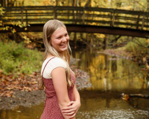 Older Teen smiling at Hubbard Valley Park Medina with fall colors and a bridge over a creek