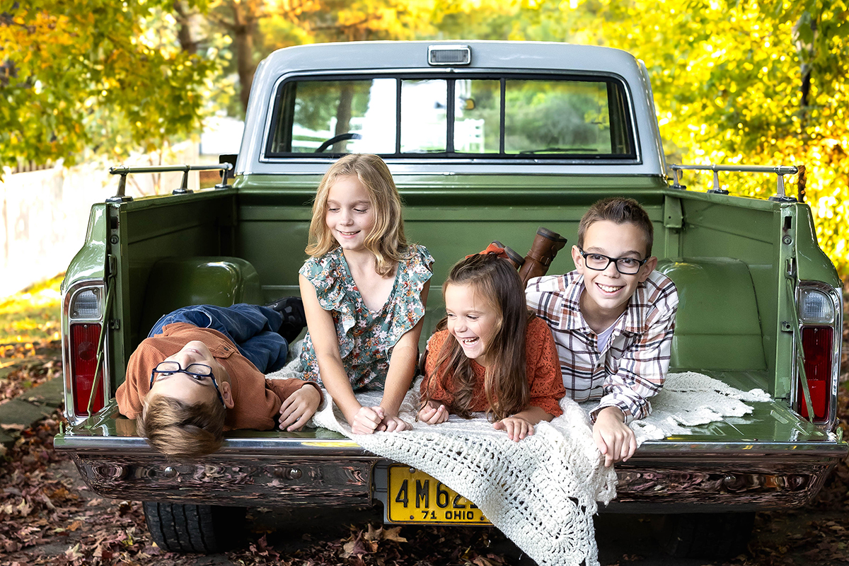 4 kids playing on the back of an old vintage truck captured in a lifestyle photograph