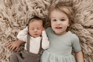 Toddler sister holding newborn baby brother 