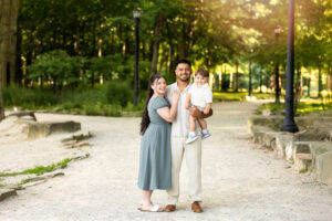 Family smiling together at coe lake on a walking path. 