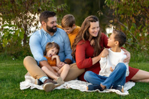 Family wearing jewel tones smiling and playing by a lake in the fall season 
