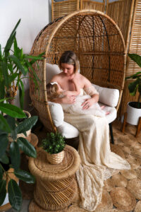 Mother breastfeeding her newborn while seated in a bohemian wicker chair, surrounded by natural textures and soft, earthy tones . a calm, intimate moment of connection and nurturing.