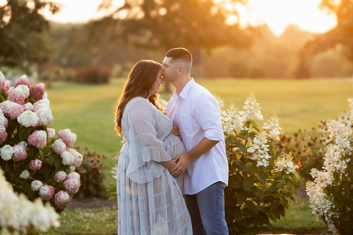 maternity session with husband kissing wife on forhead. in a deep beautiful sunset.