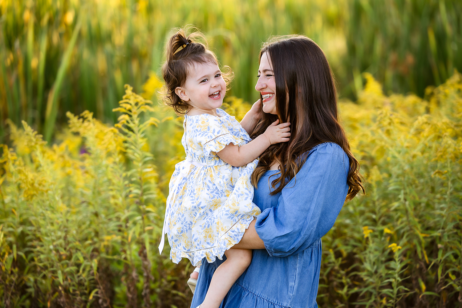 mom in dusty blue dress holding her laughing daughter, posing in golden ragweed fields near Cleveland.