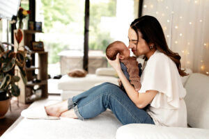 mom holding her baby nose to nose, snuggling on the couch at their medina in home photo session 