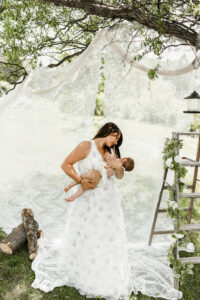 Mom nursing daughter with white lace clothes line hanging up. 