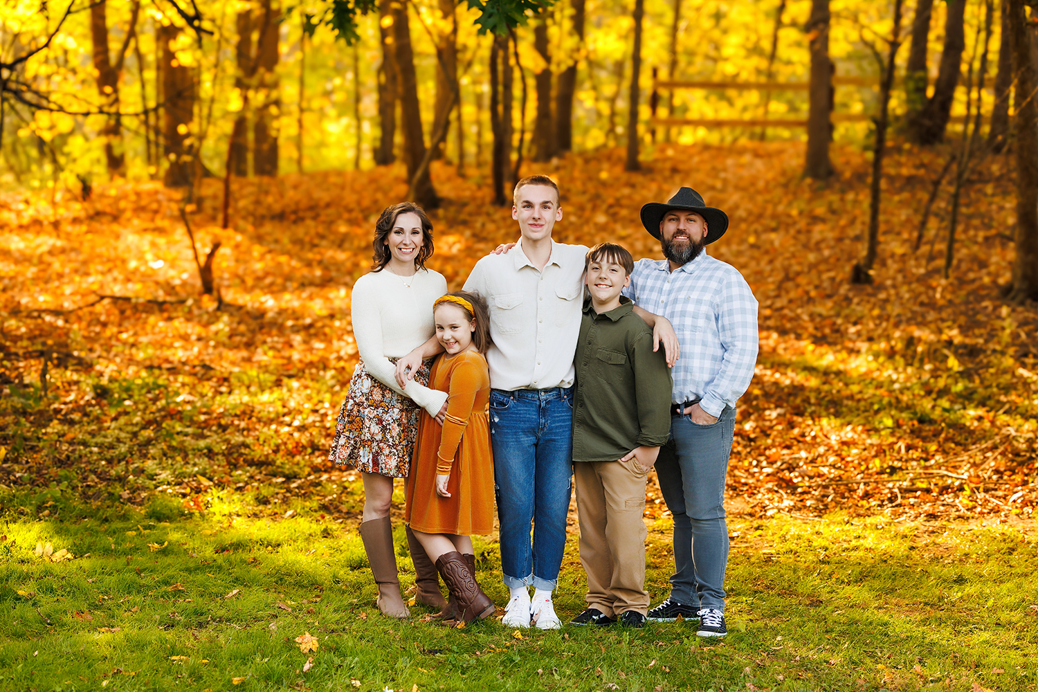 Family posing smiling at the camera in beautiful fall weather