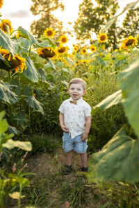 Little boy smiling at camera in beautiful fall sunflowers 