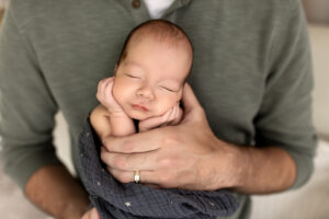newborn baby cuddling on bed during his cleveland photo session