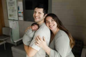 Family smiling showing off their newbaby at their fresh 48 newborn session at cleveland hospital 