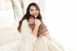mom cuddling her sleeping newborn at photo session dressed in neutrals