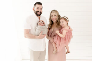 Family wearing soft beige and creams and blush outfits for newborn photos in studio, styled by Cleveland newborn photographer Danielle Ashley
