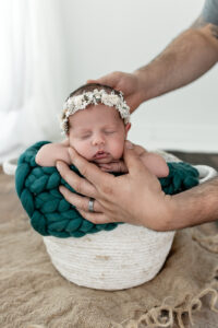 Dad safely holding newborn baby in bucket during her cleveland newborn photoshoot 