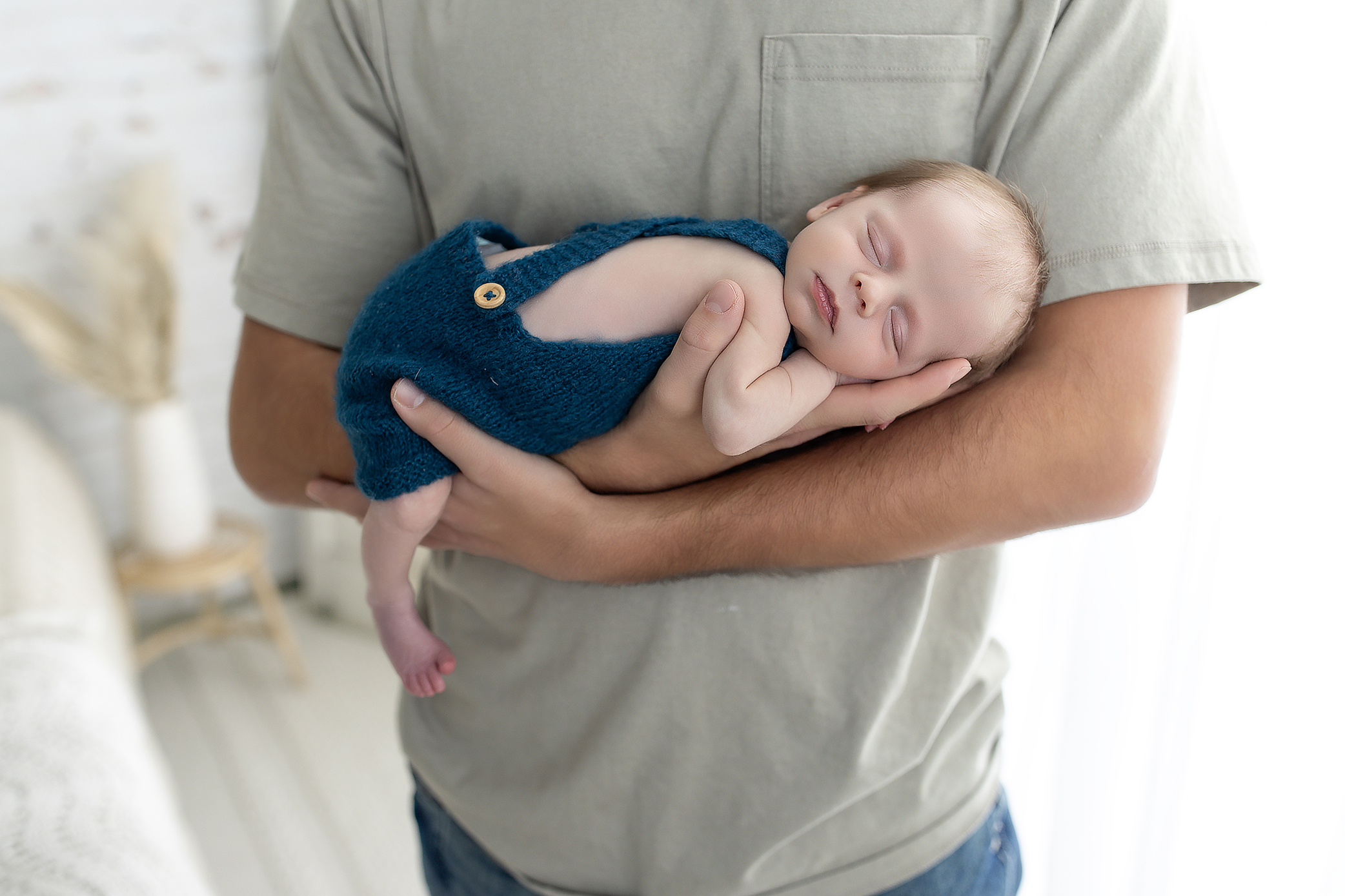 Parent supporting newborn baby during a posed photo for safety in Medina photography studio