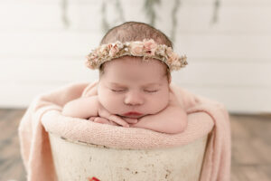 Newborn baby safely posed in a bucket with support and weight at bottom by Cleveland newborn photographer