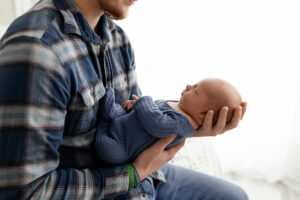 father holding his newborn baby boy looking down at him smiling during his cleveland lifestyle session 