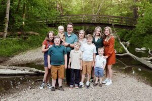 Family poses at spring photo session by the creek and bridge at hubbard valley park medina county ohio 