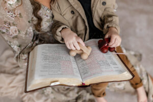 Child playing with wooden toys as mom reads him the Easter Story of Jesus in the bible at Danielle Ashley Photography Studio in Medina, ohio 