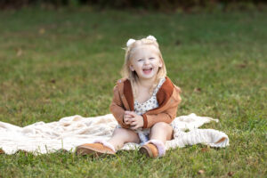 Little girl laughing at pumpkin farm during a fall birthday celebration near Medina Ohio